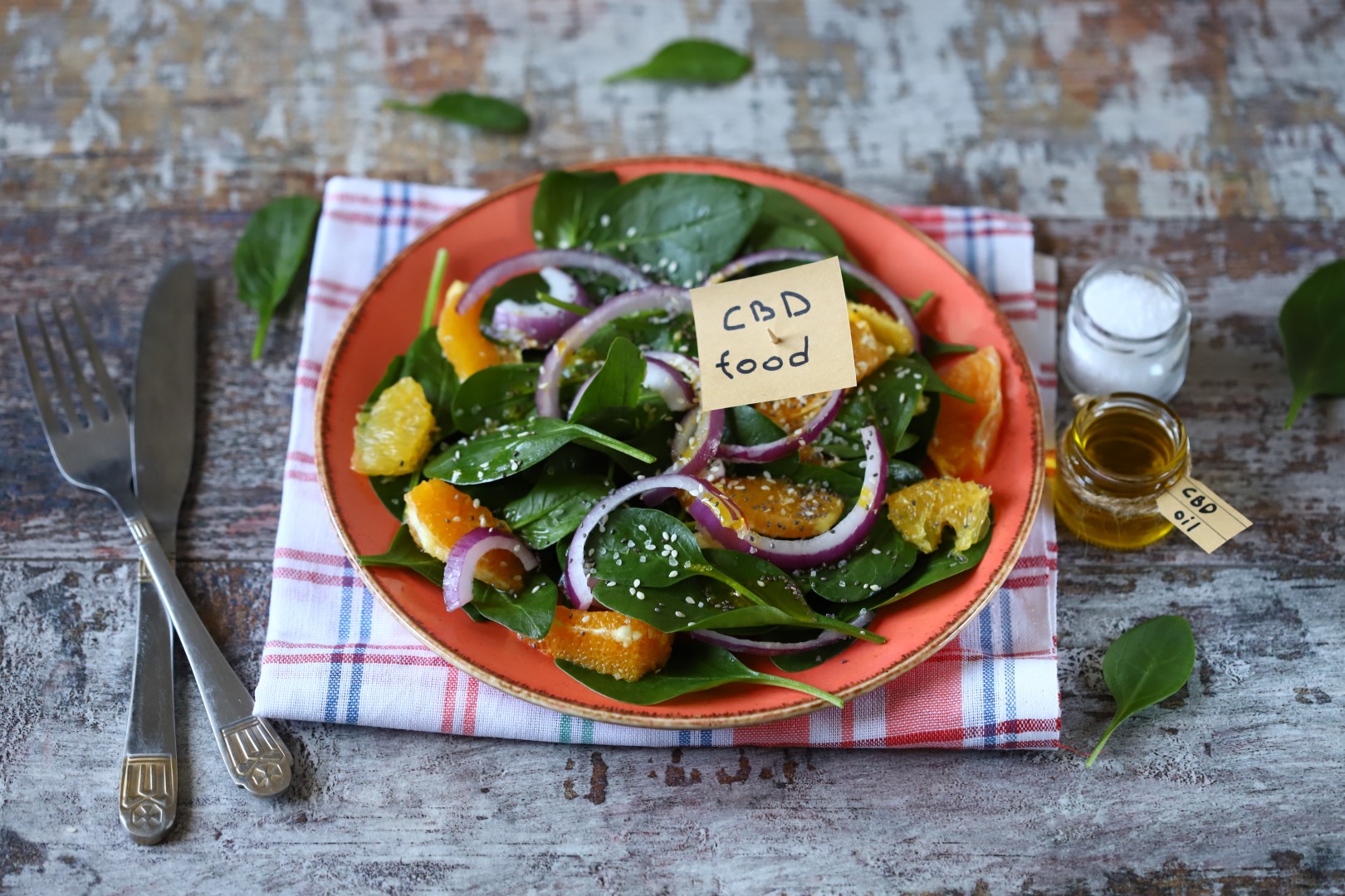 Selective focus. A note with the inscription CBD food in a plate of salad. Cannabis oil salad. Healthy salad with spinach and orange.